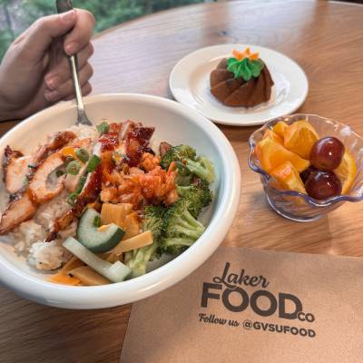 Rice bowl, fruit, and dessert on a table with a Laker Food Co logo napkin